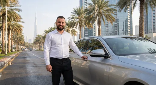 Comfort Drive driver in uniform standing beside a client's car in Dubai